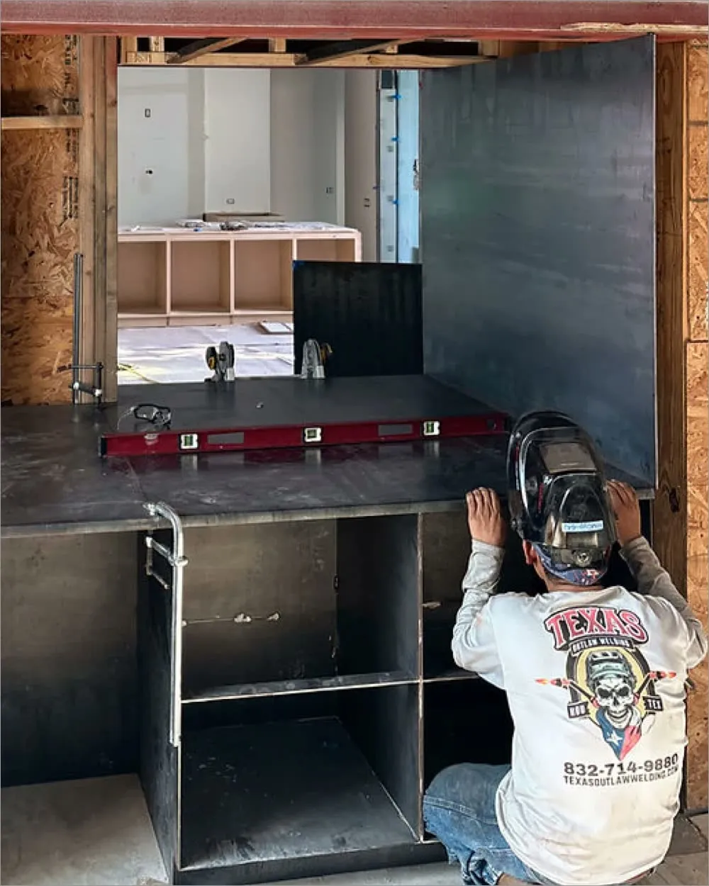 approach-fitup.webp A Texas Outlaw Welding fabricator levelling a steel counter assembly on site during a buildout