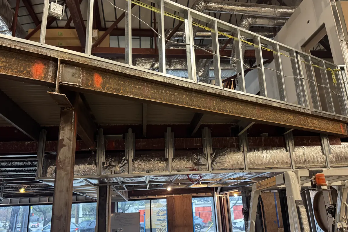 Structural steel beam, support columns and guardrail installed above a ground floor