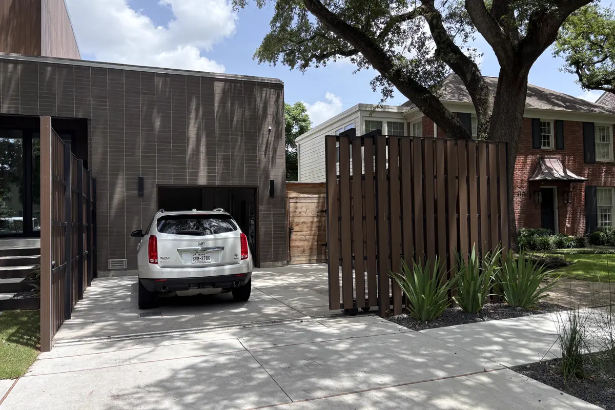 Timber-clad steel driveway gate and steel privacy screen at a modern Houston home